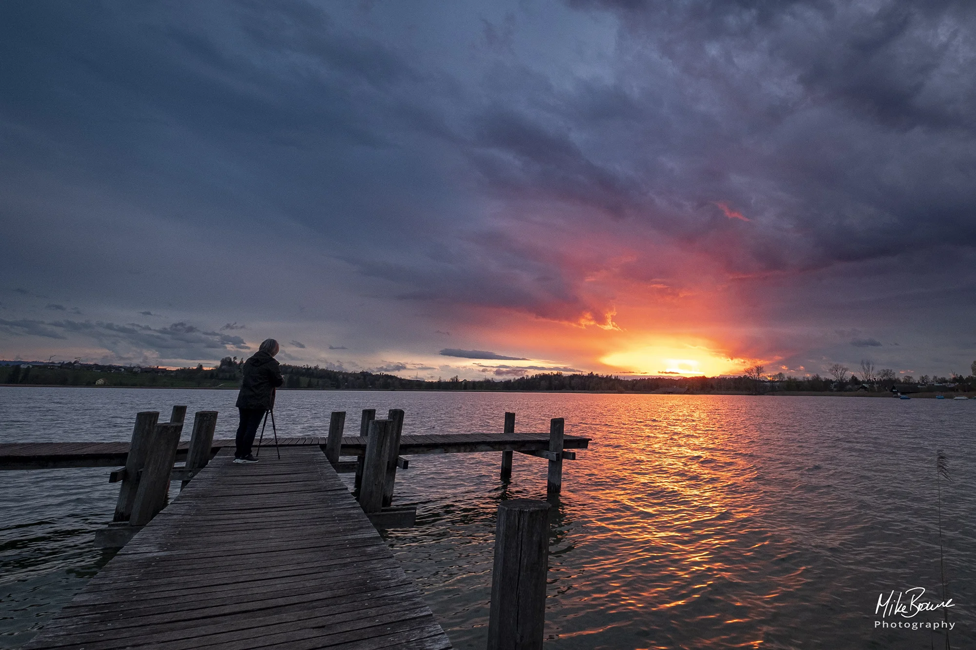 Silhouette of woman photographer against storm clouds at sunset