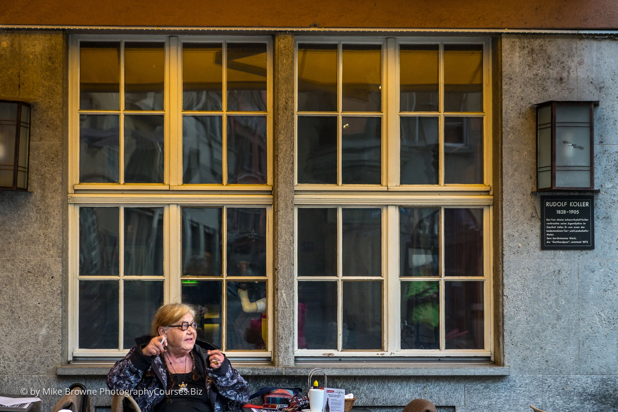 Older woman wearing cool glasses smoking cigarette outside a cafe in Zurich