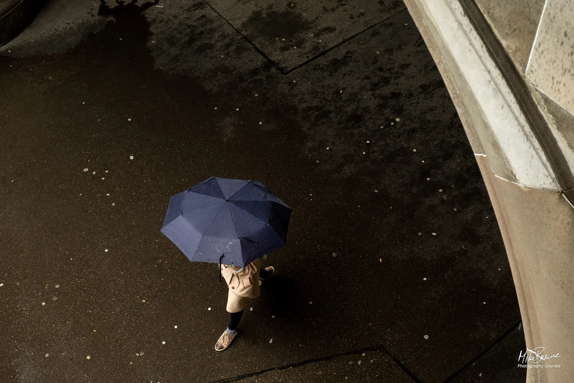 Woman with umbrella walking out from under a bridge in Zurich