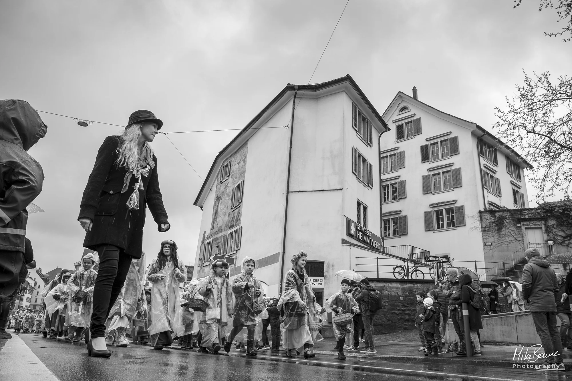 Woman in a hat leading Sechseläuten children\'s parade in the rain