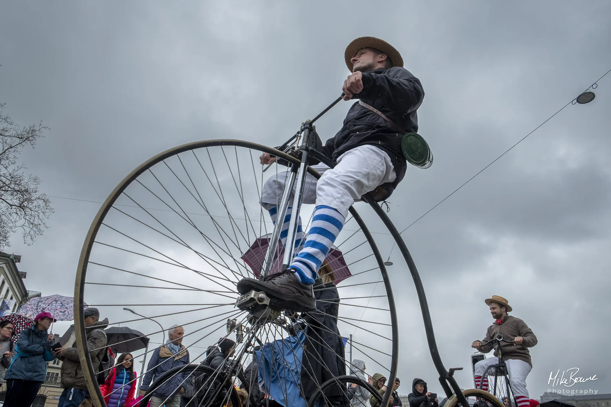 Man riding vintage penny farthing bicycle agains cloudy sky