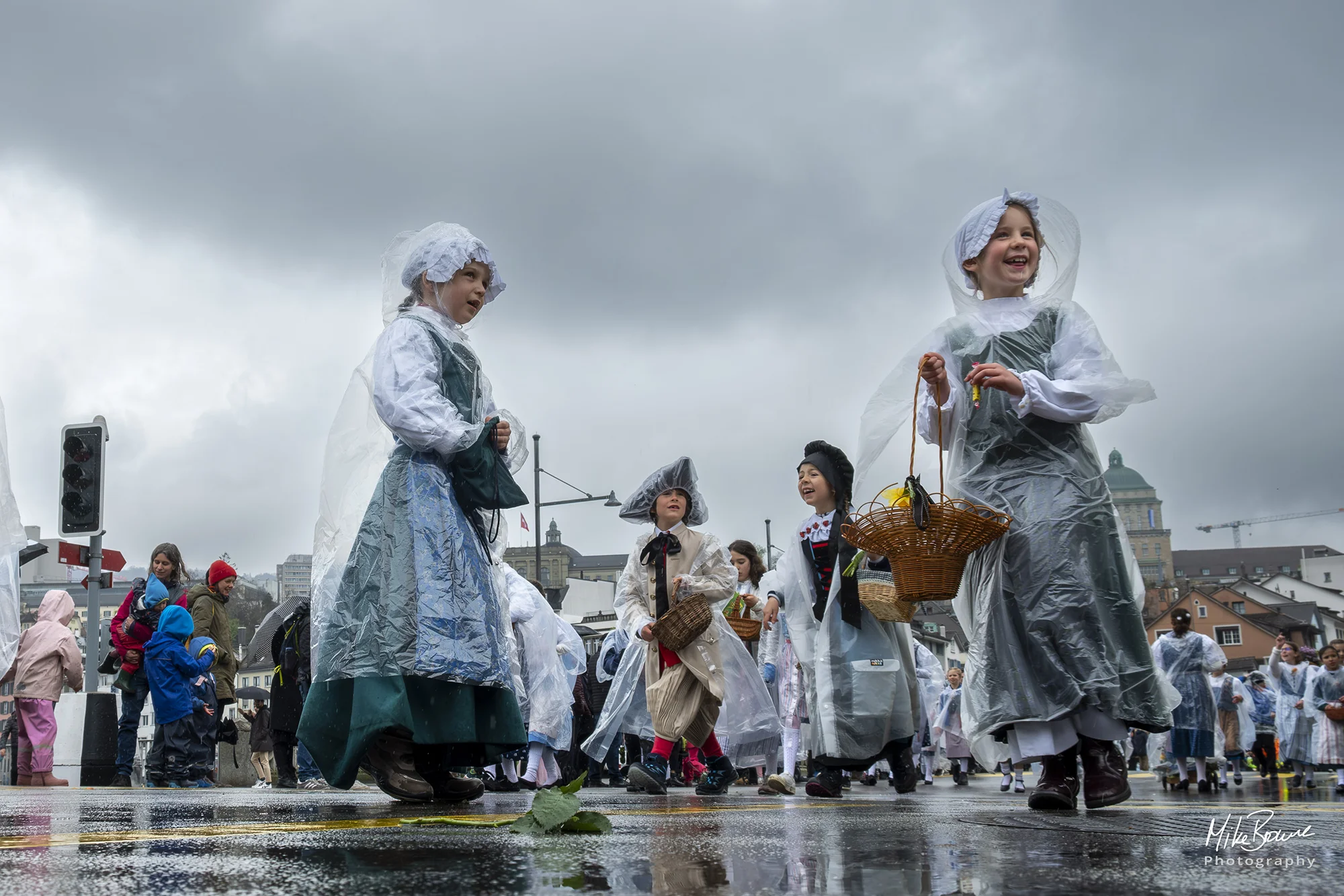 Laughing children wearing plastic coats in the rain at Sechseläuten parade