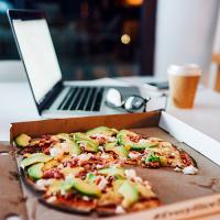 pizza in a box with a slice missing and a laptop in the background