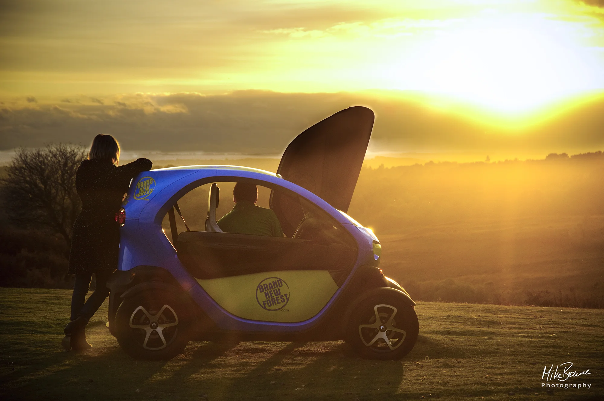 Man and woman looking at sunset from a small Renault Twizzy electric car