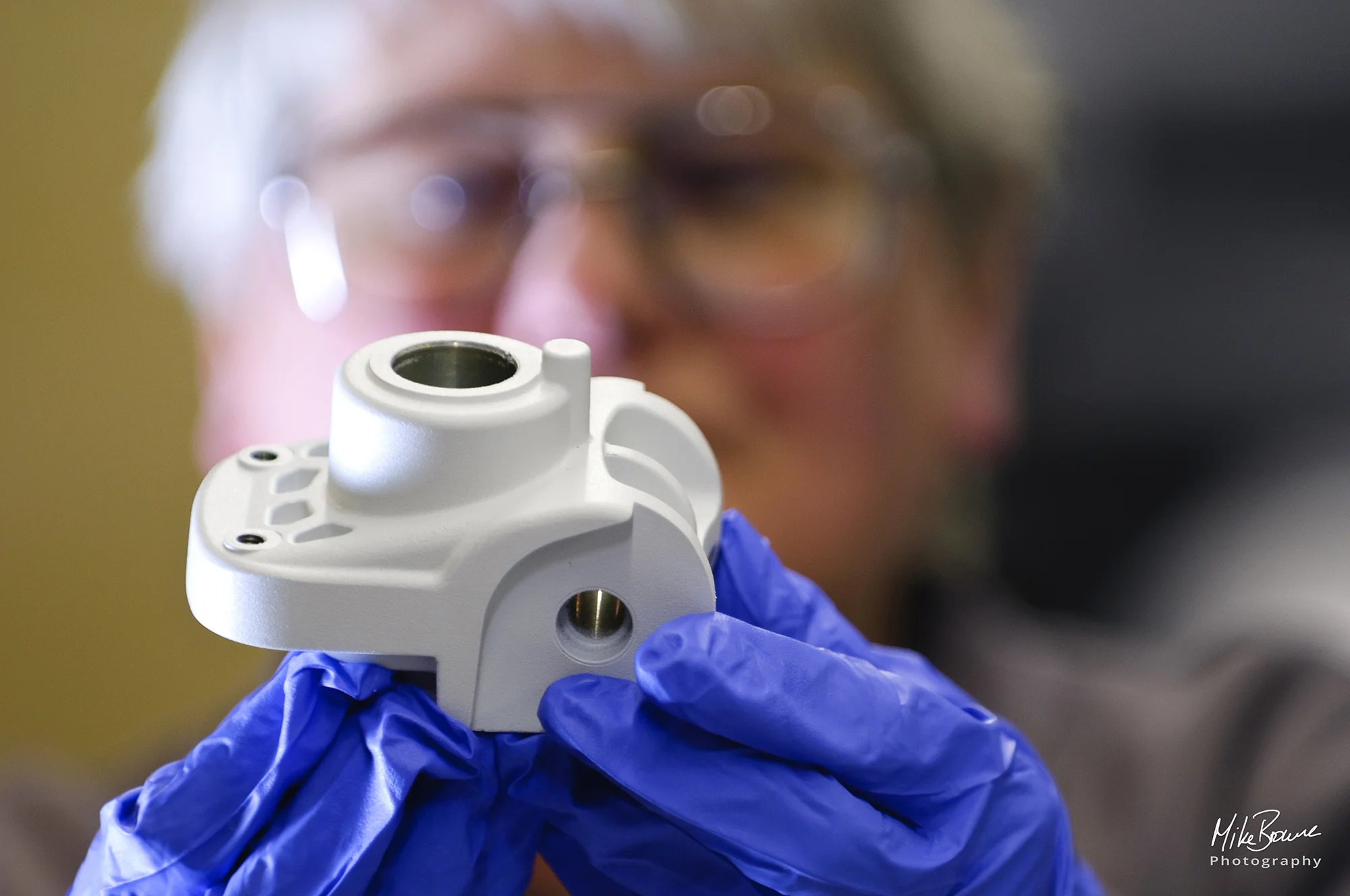 Person wearing blue protective gloves inspecting a component for quality control