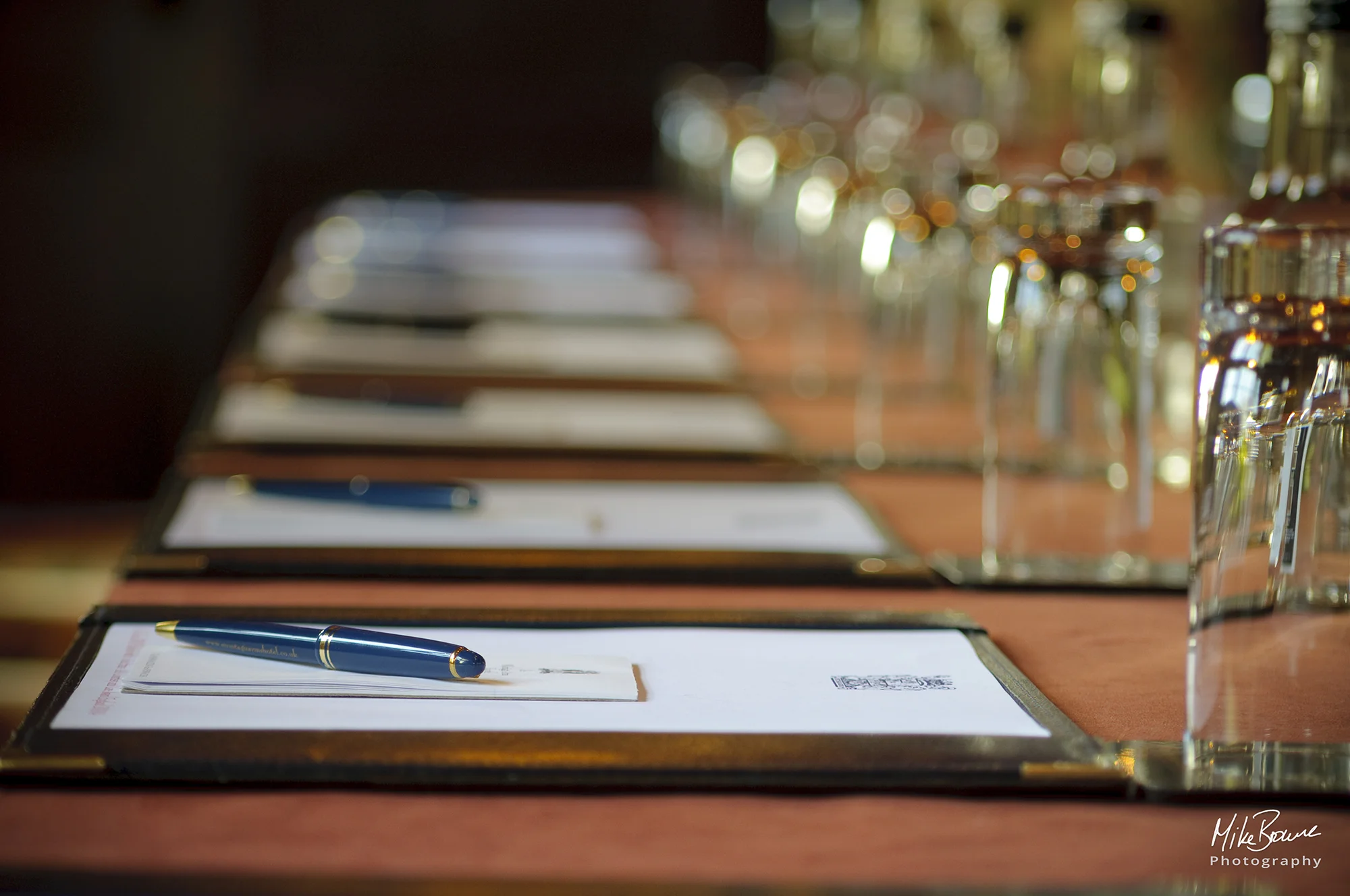 Pens, note pads and water glasses set out for a business meeting in a function room