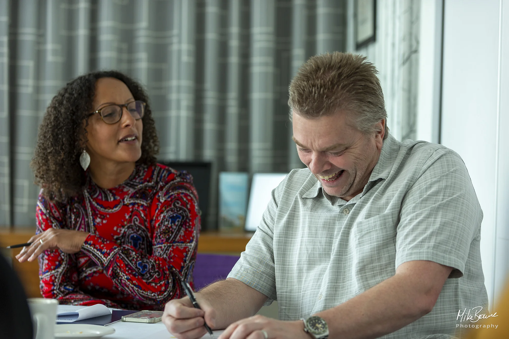 Man laughing at a woman\'s comment during a conversation at a business meeting