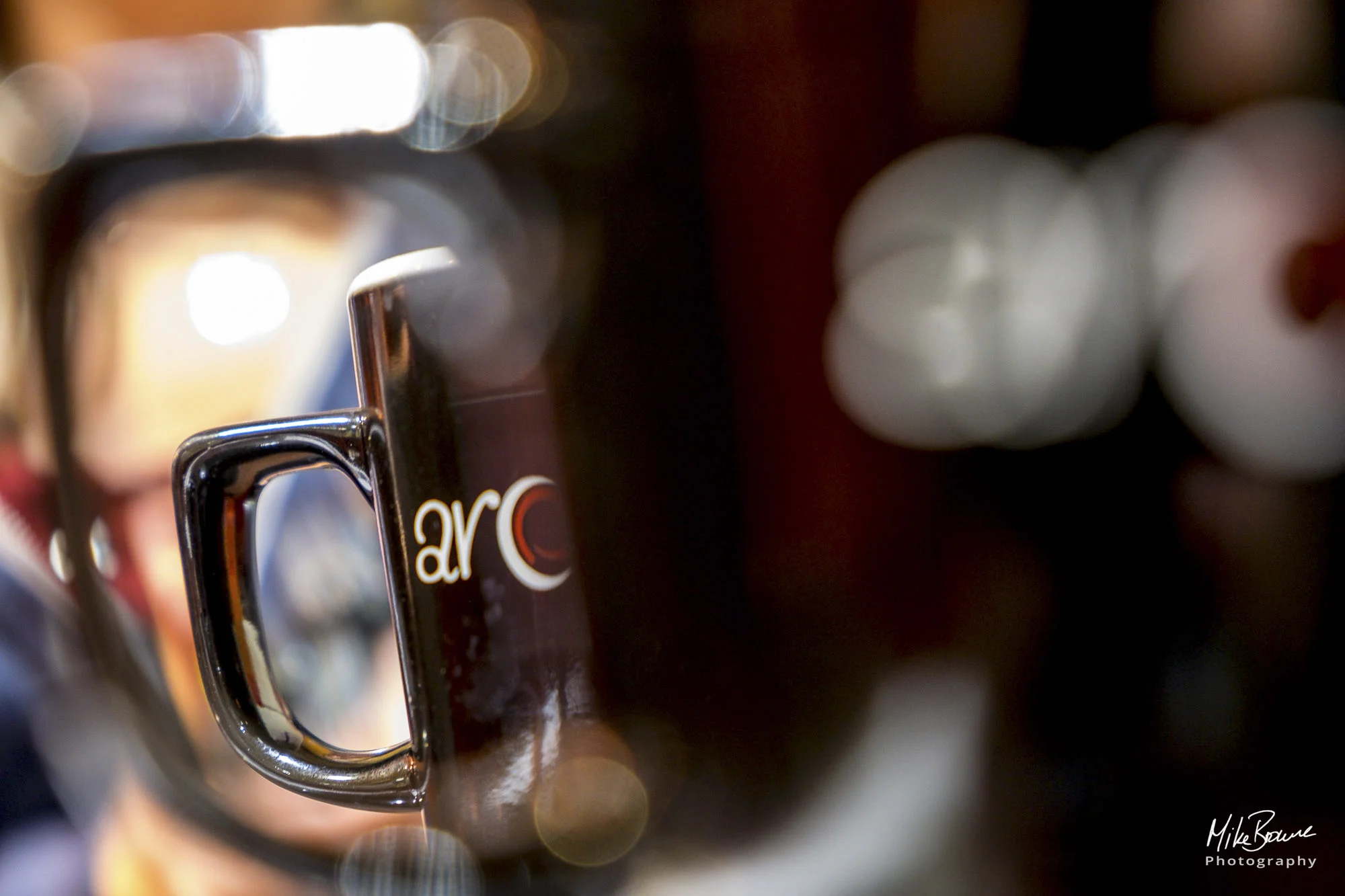 One branded coffe mug viewed through the handle of another