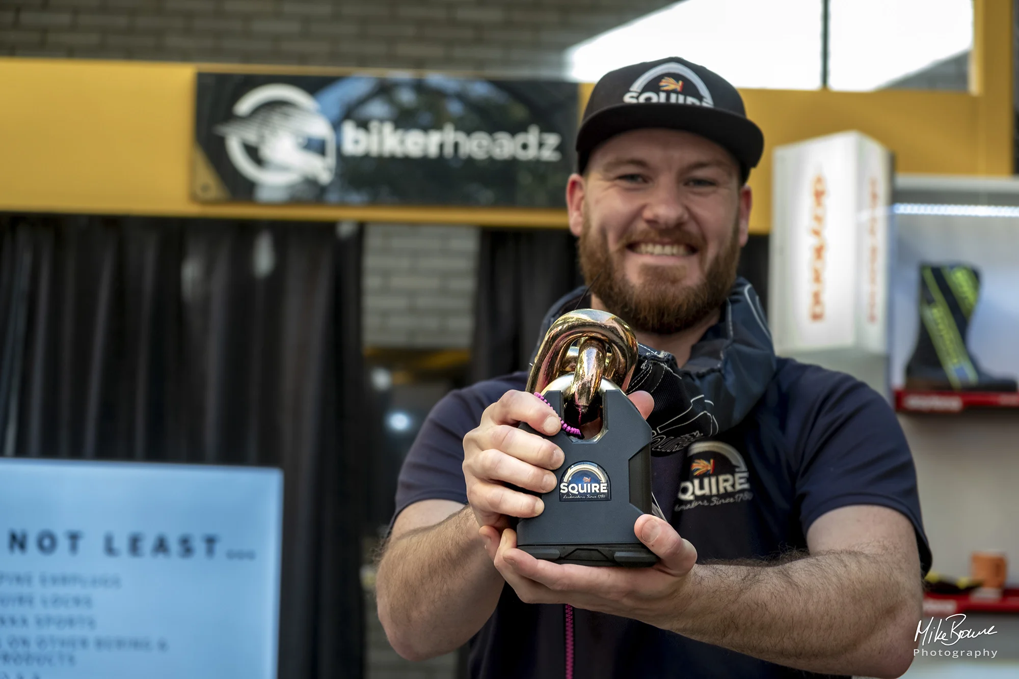 Bearded man wearing baseball cap with Squire logo holding a large Squire motorcycle security lock