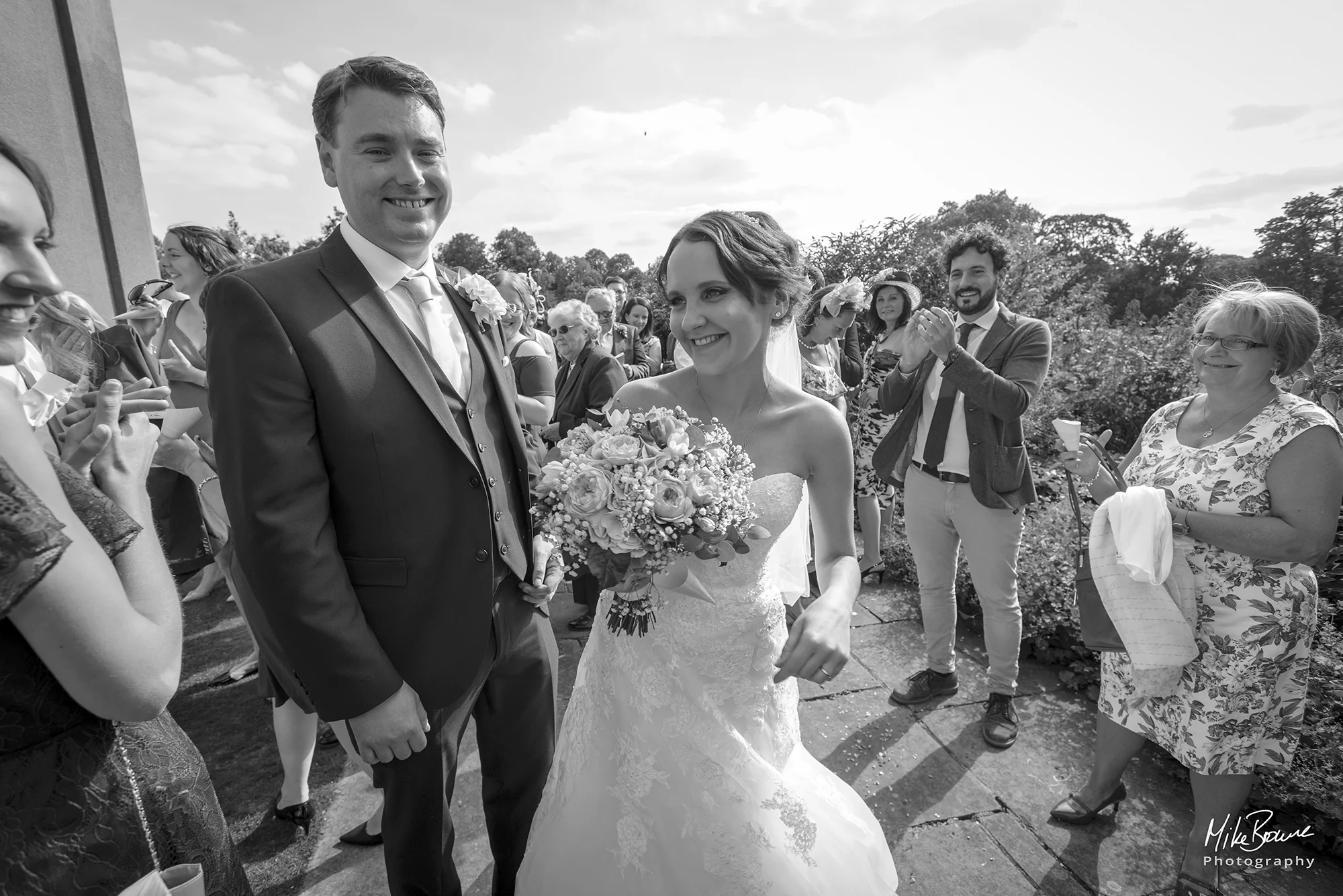 Smiling couple being applauded by friends on their wedding day