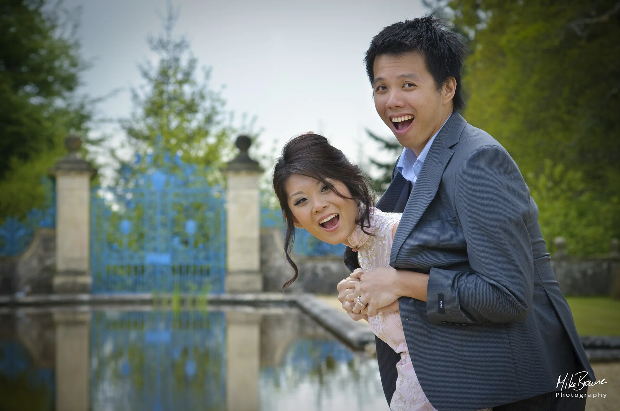 Bride and groom laughing and embracing by a still lake