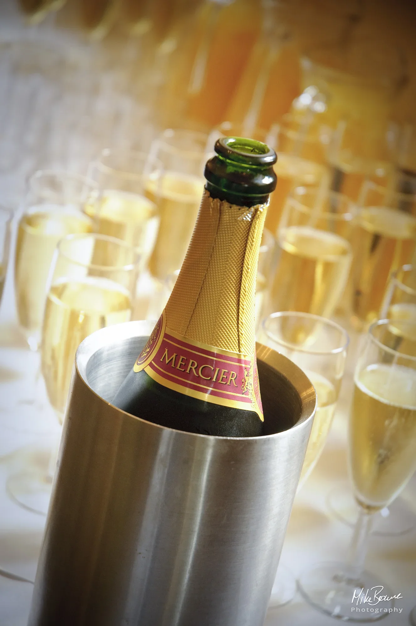 Champagne bottle in an ice bucket with many glasses of champagne in background