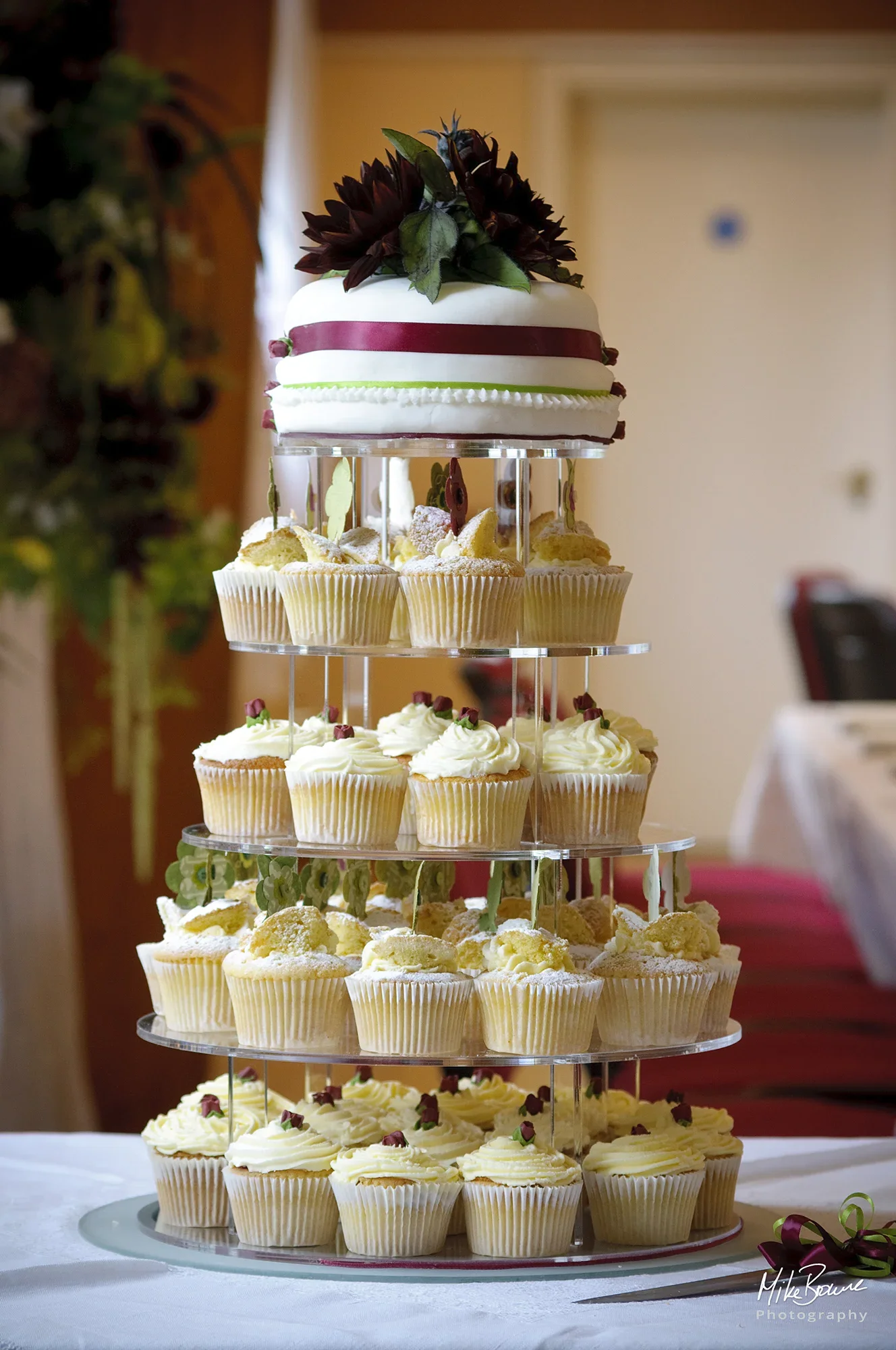 A 5 tiered wedding cake with decorative cupcakes on lower 4 tiers