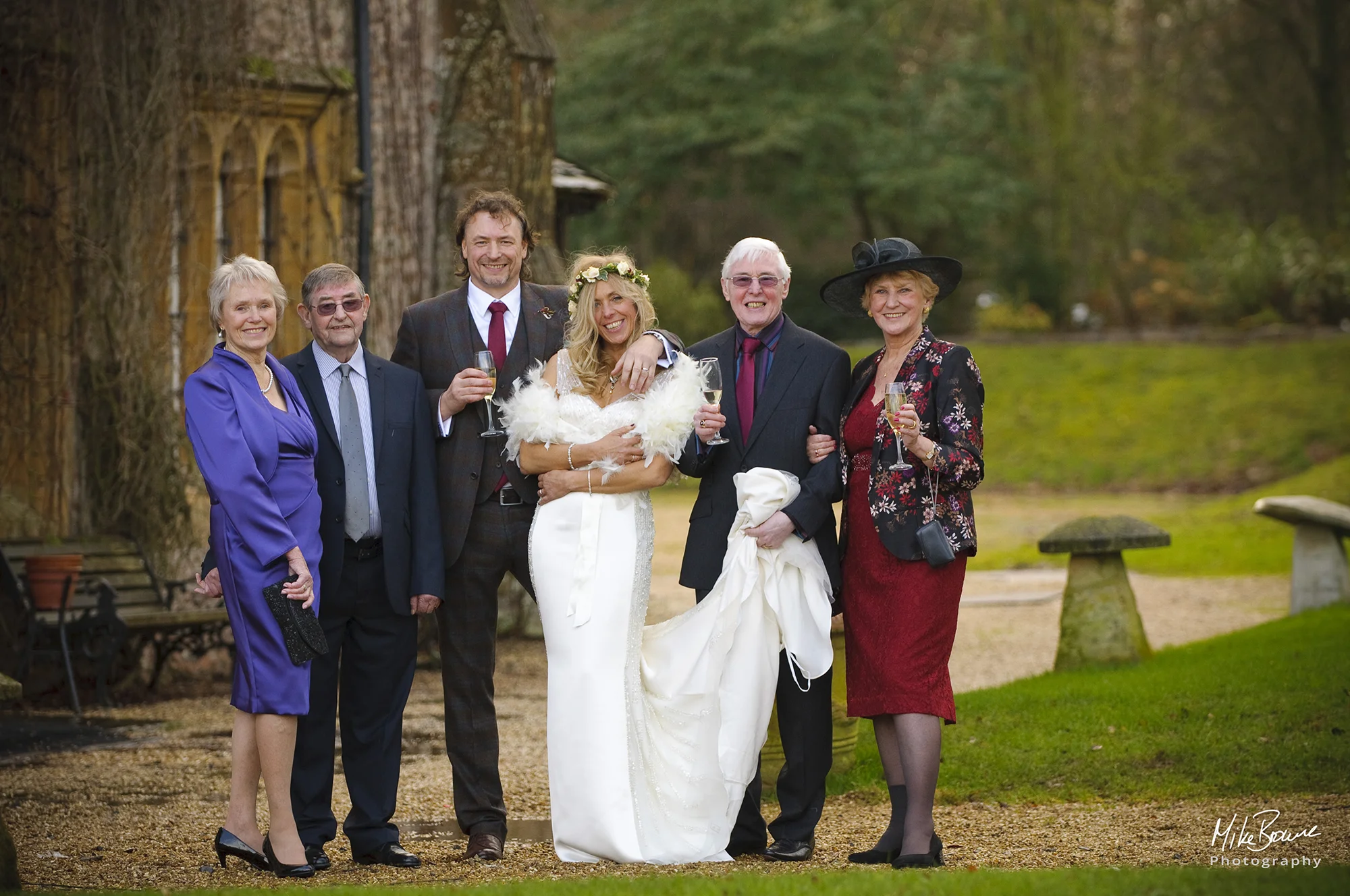 Man and woman dressed for a wedding pose with their parents in a winter garden