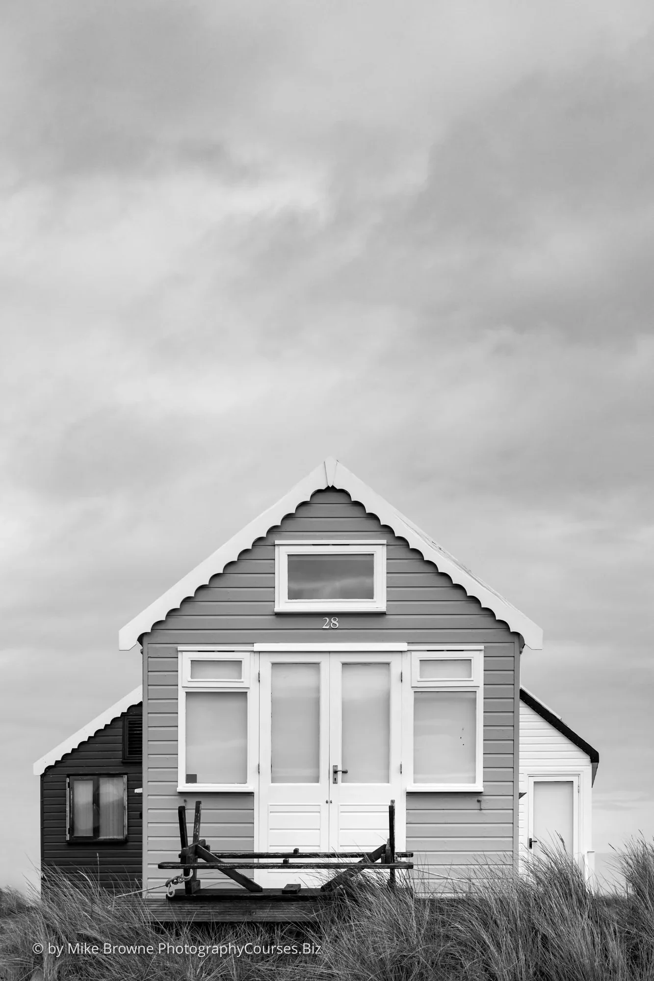 Three British beach huts and cloudy sky