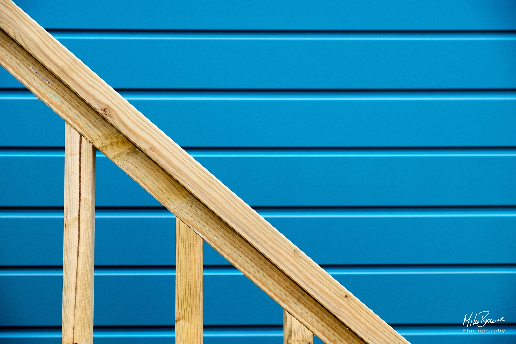 Wooden hand rail on side of a blue beach hut