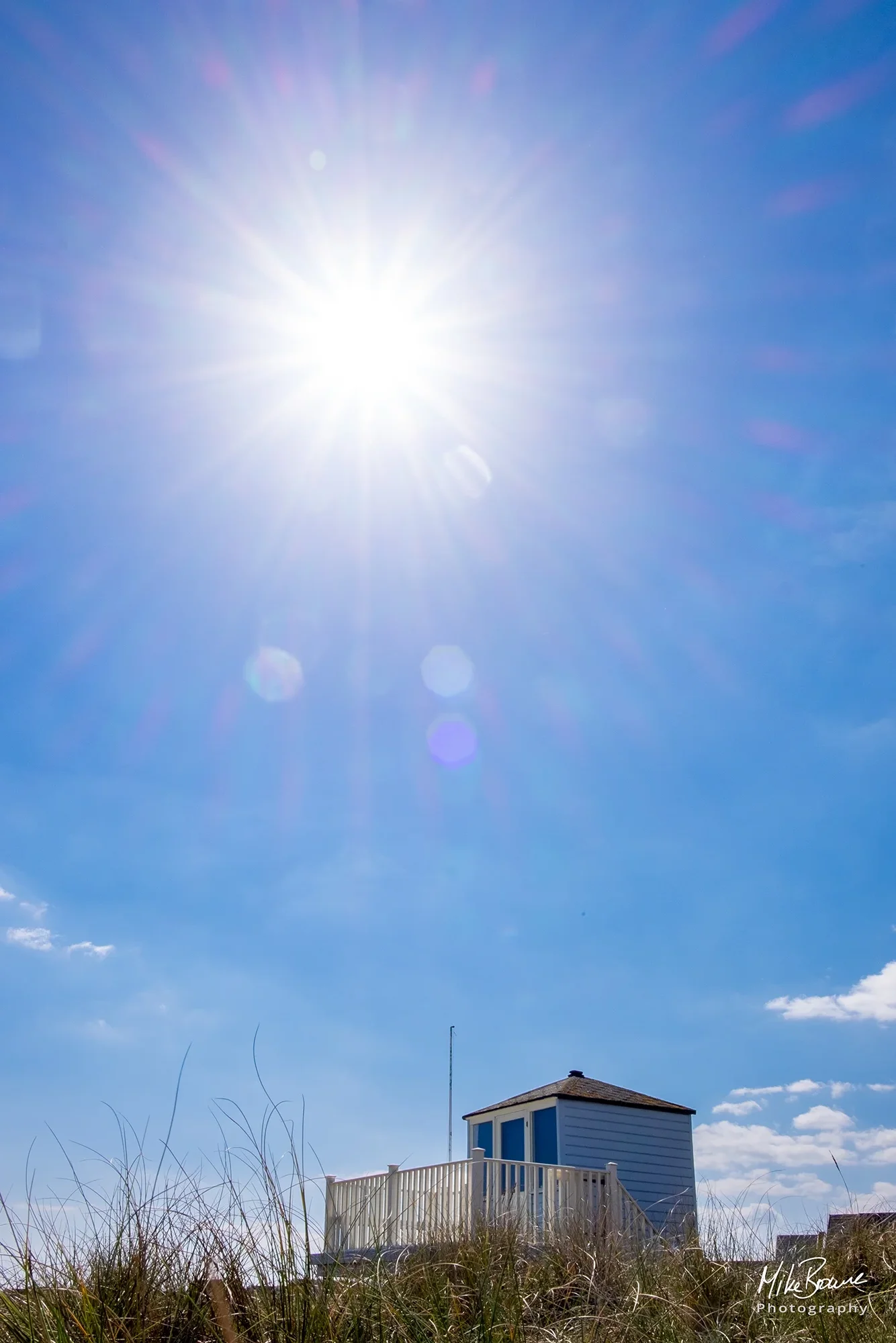 Single British beach hut with sun shining in a blue sky