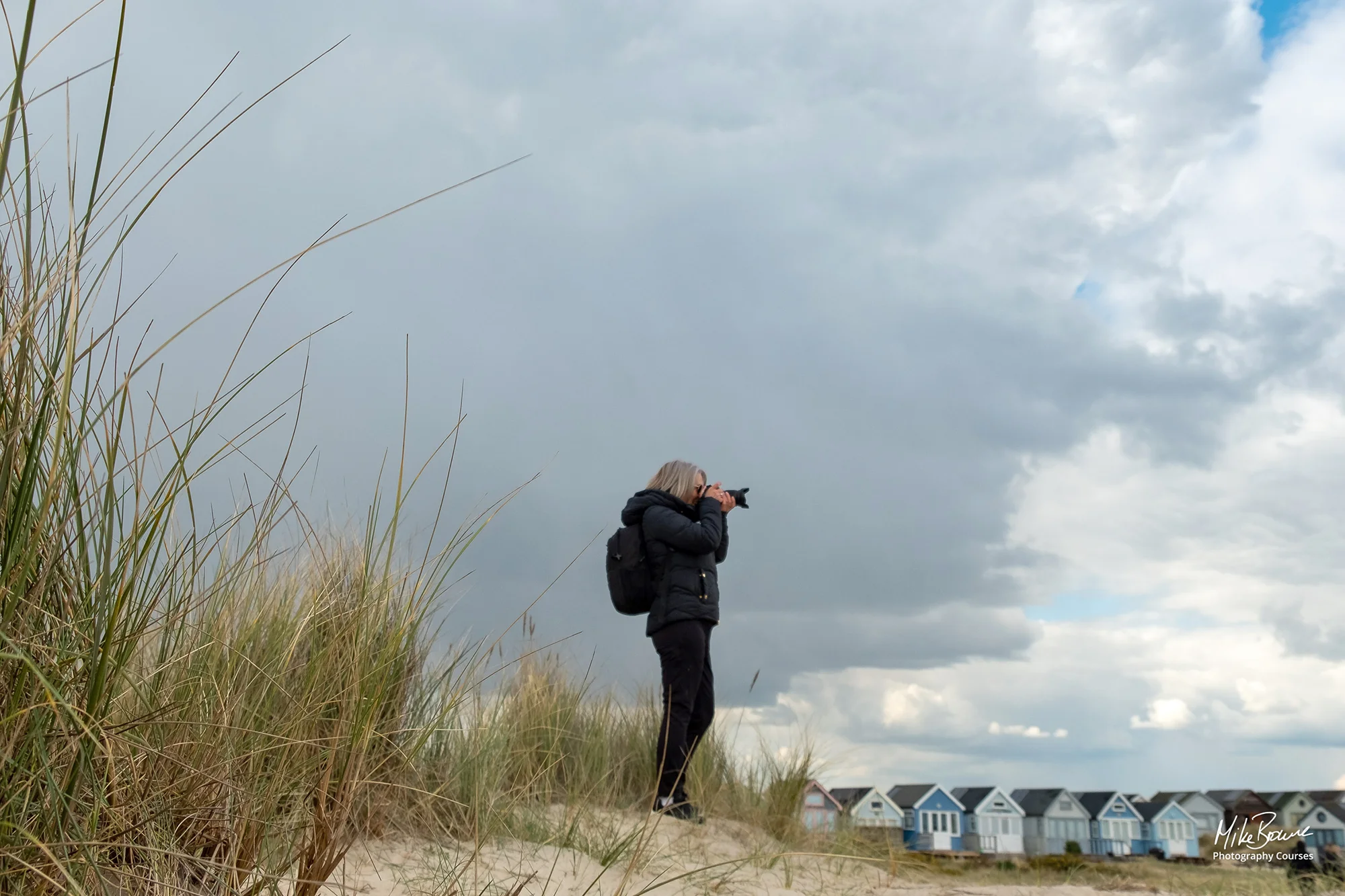 Lone photographer standing on sand dune with long grasses