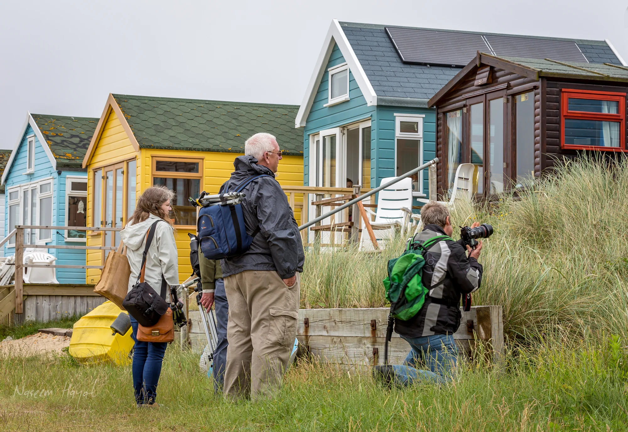 Photographers photographing colourful beach huts at Hengistbury Head, UK