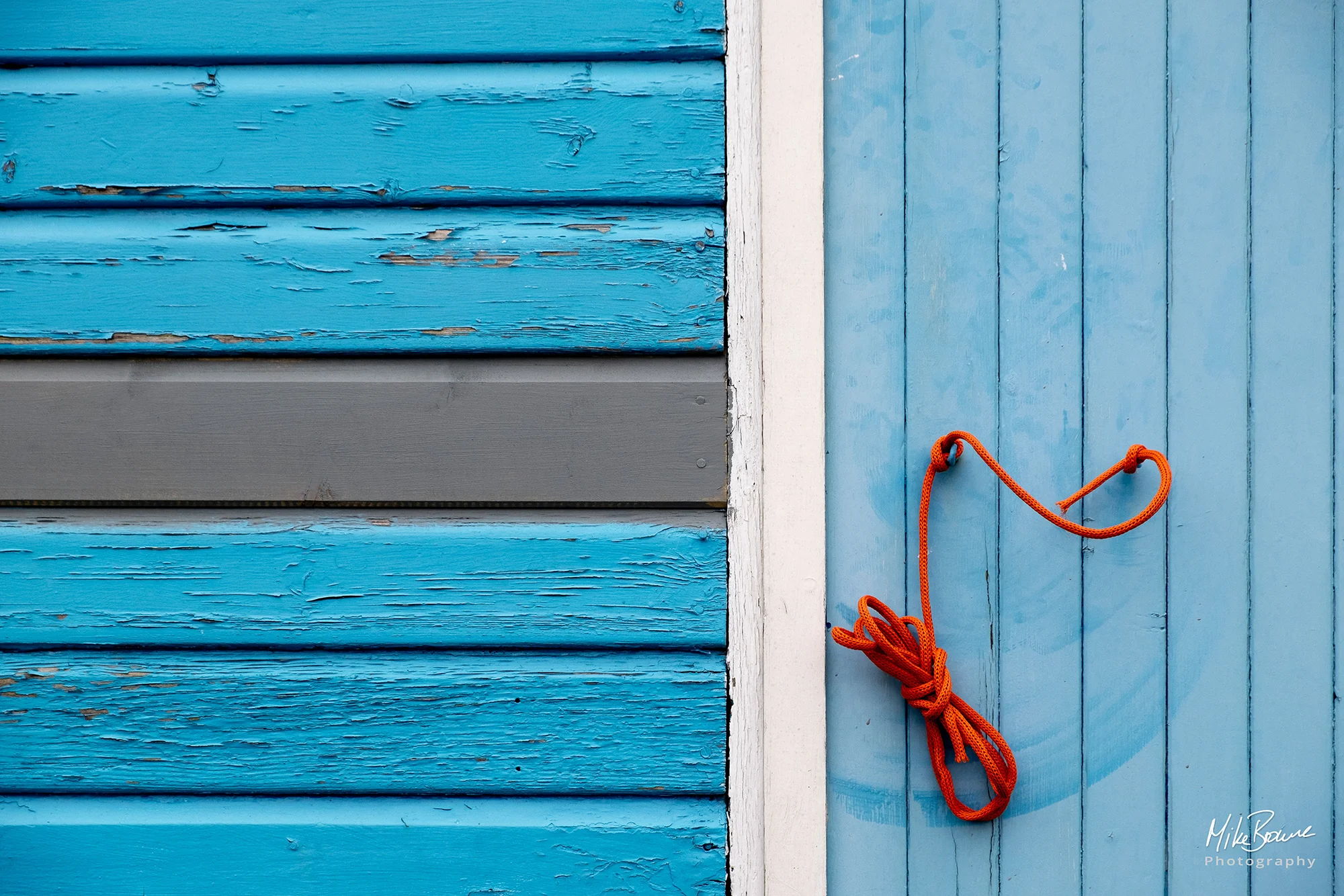 Orange rope hanging on blue wooden slats