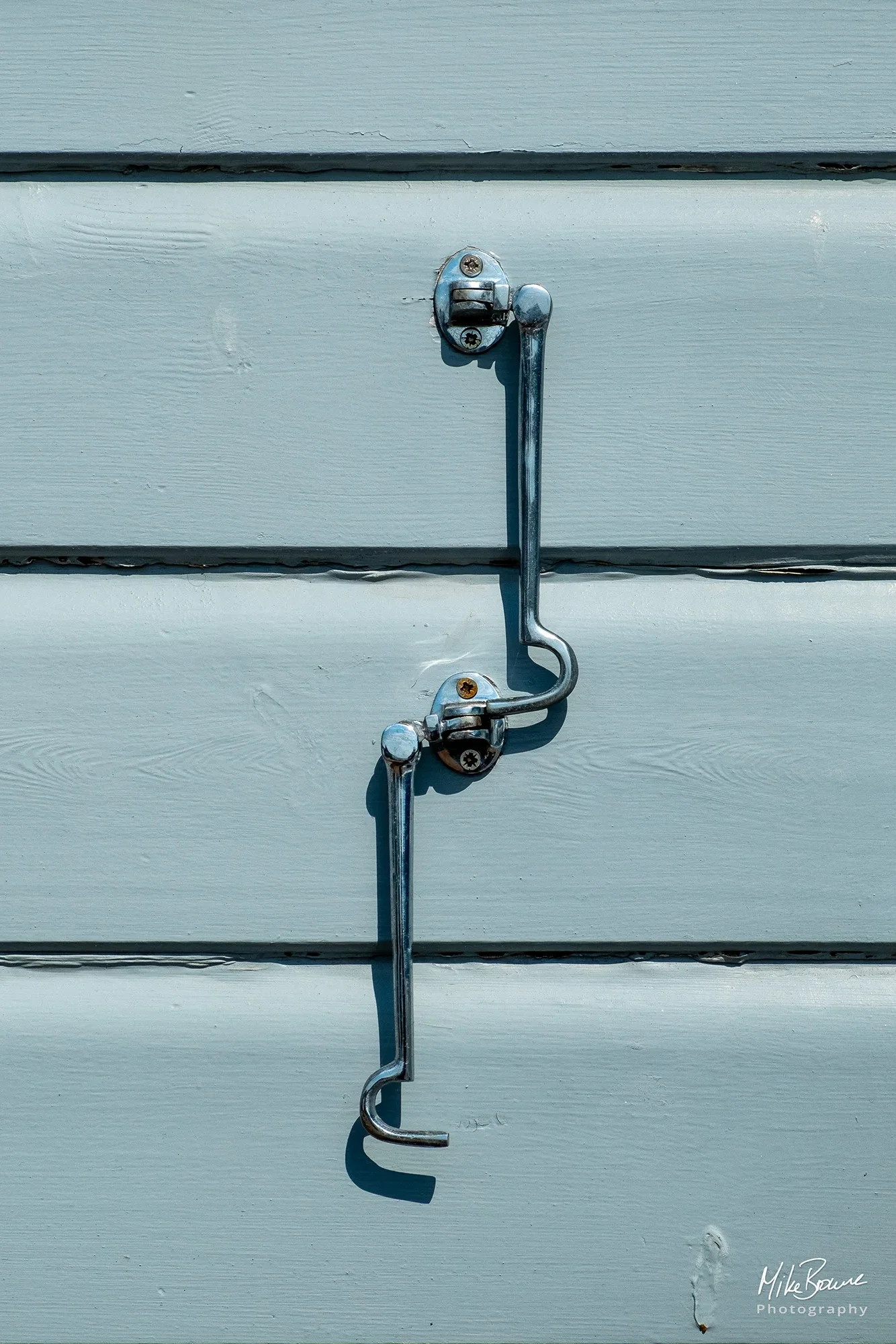 two silver door hooks fixed to grey planking