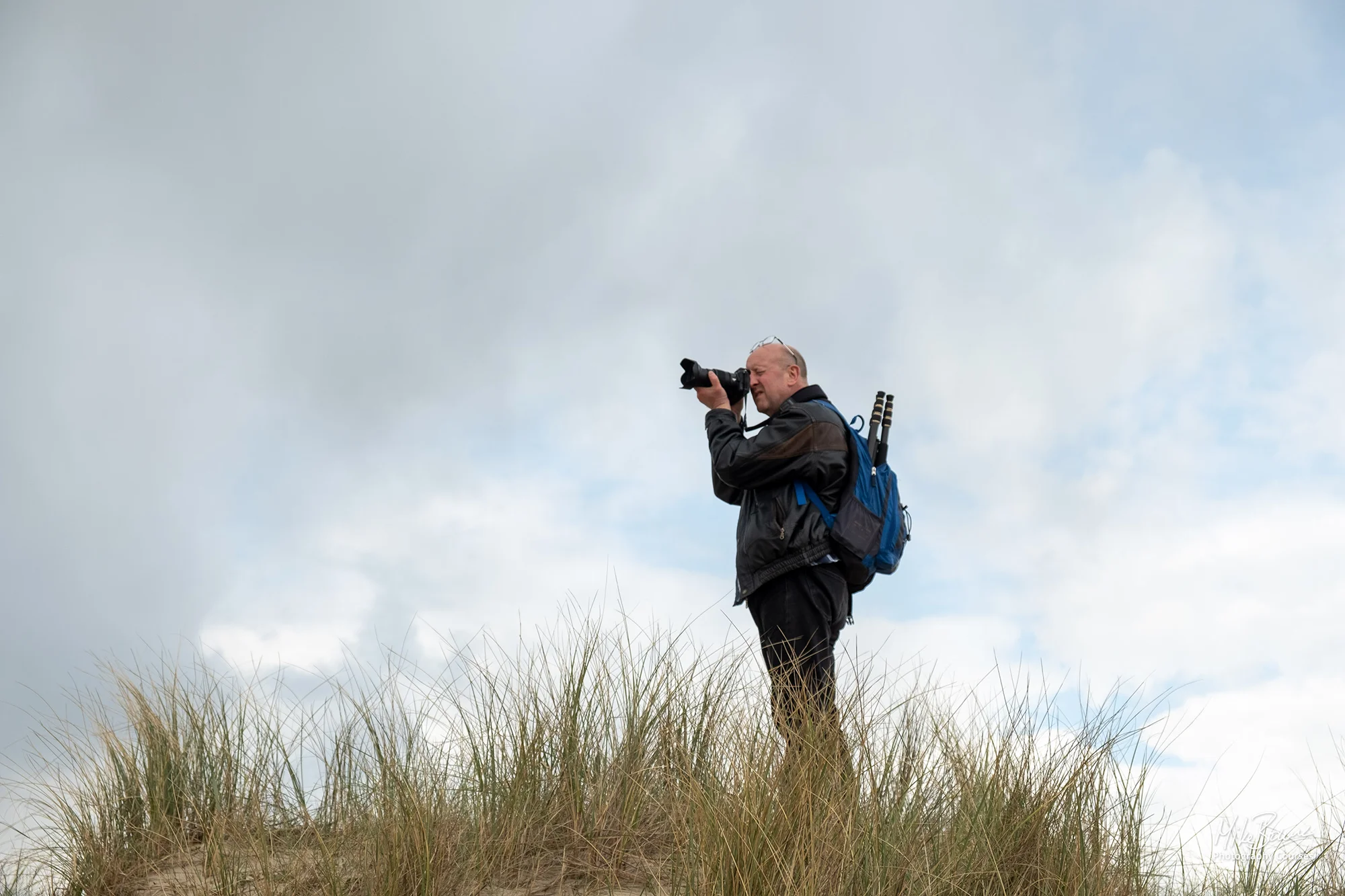 Male photographer standing on sand dune taking a photograph