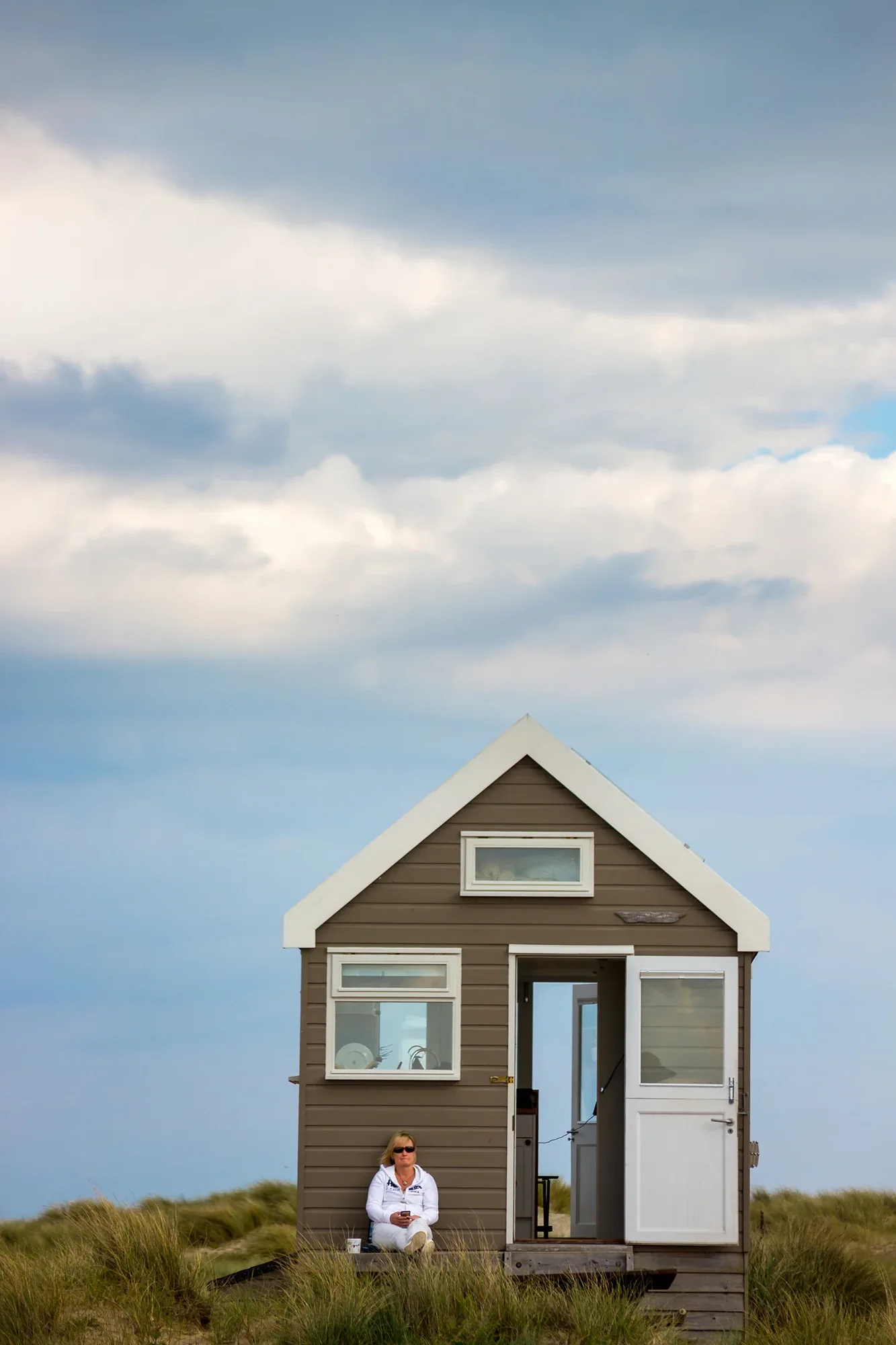 A woman sitting alone on steps of a British beach hut