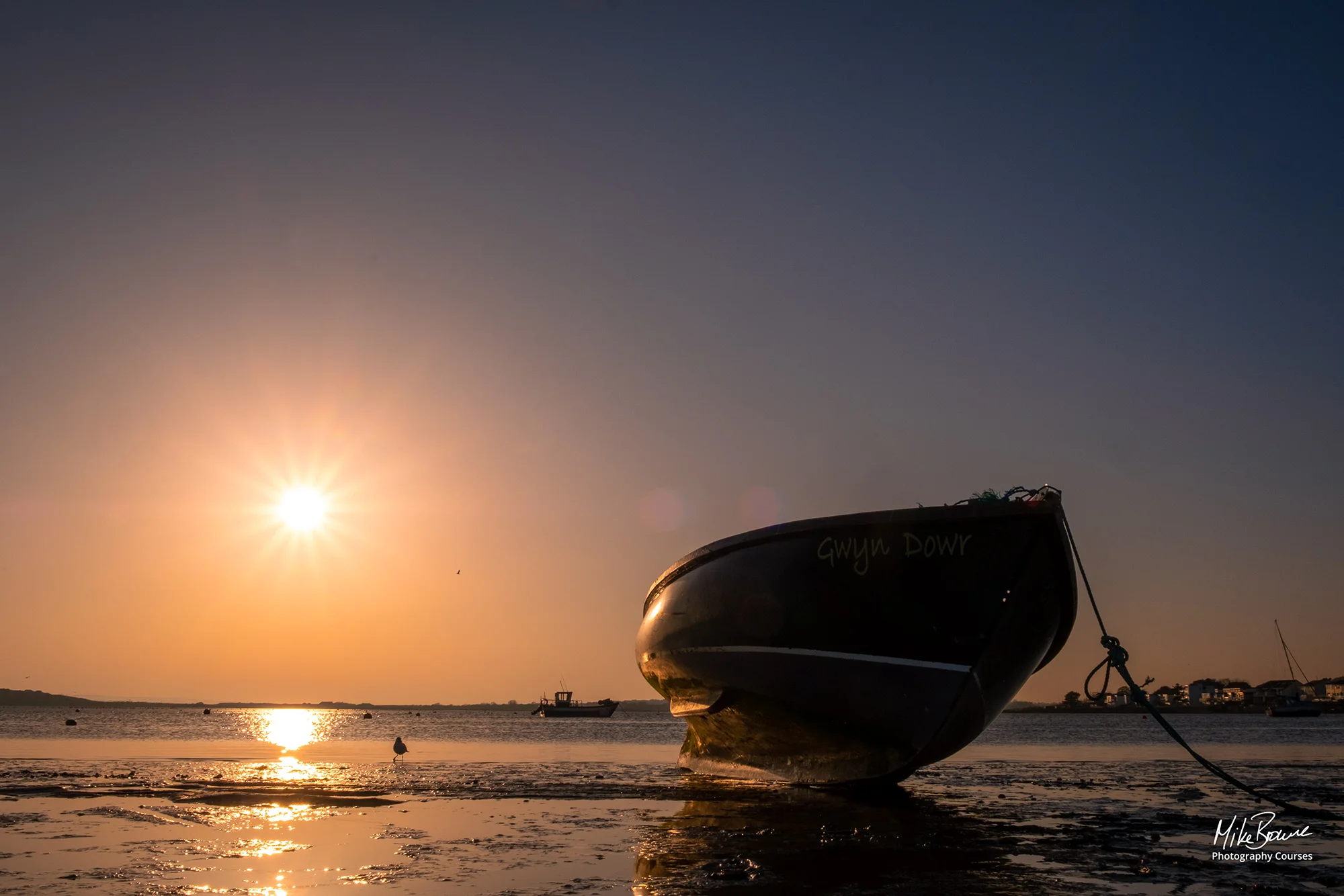 Small boat on mudflats at low tide during sunset