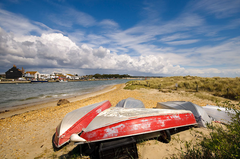 Well used small boats upturned on an empty beach