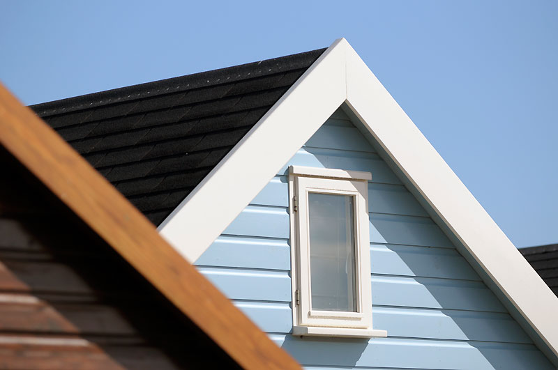 Apex of blue beach hut showing white window frame