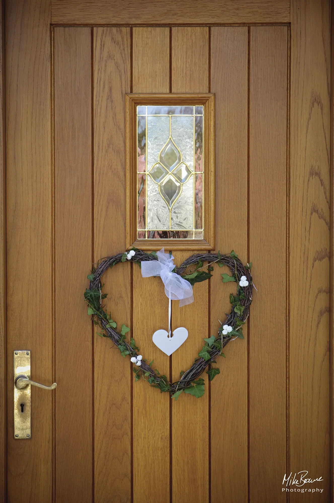 Front door of a house with a heart shaped design in pink flowers