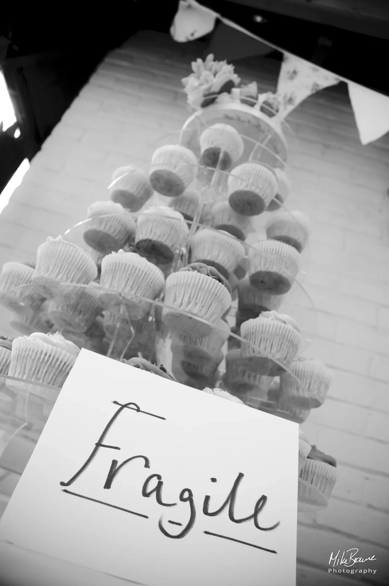 The word Fragile on a hand written sign in front of a wedding cake