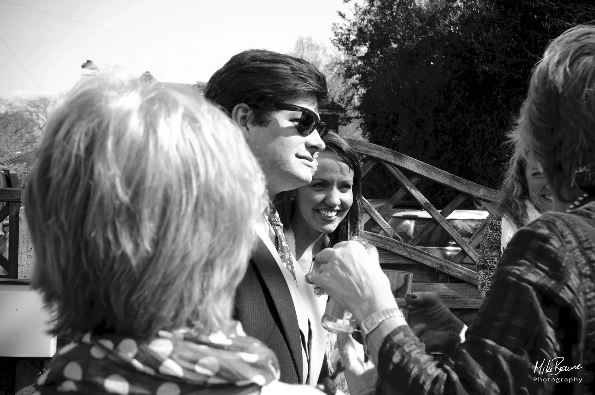 group of five friends talking in the sunshine of a pub garden