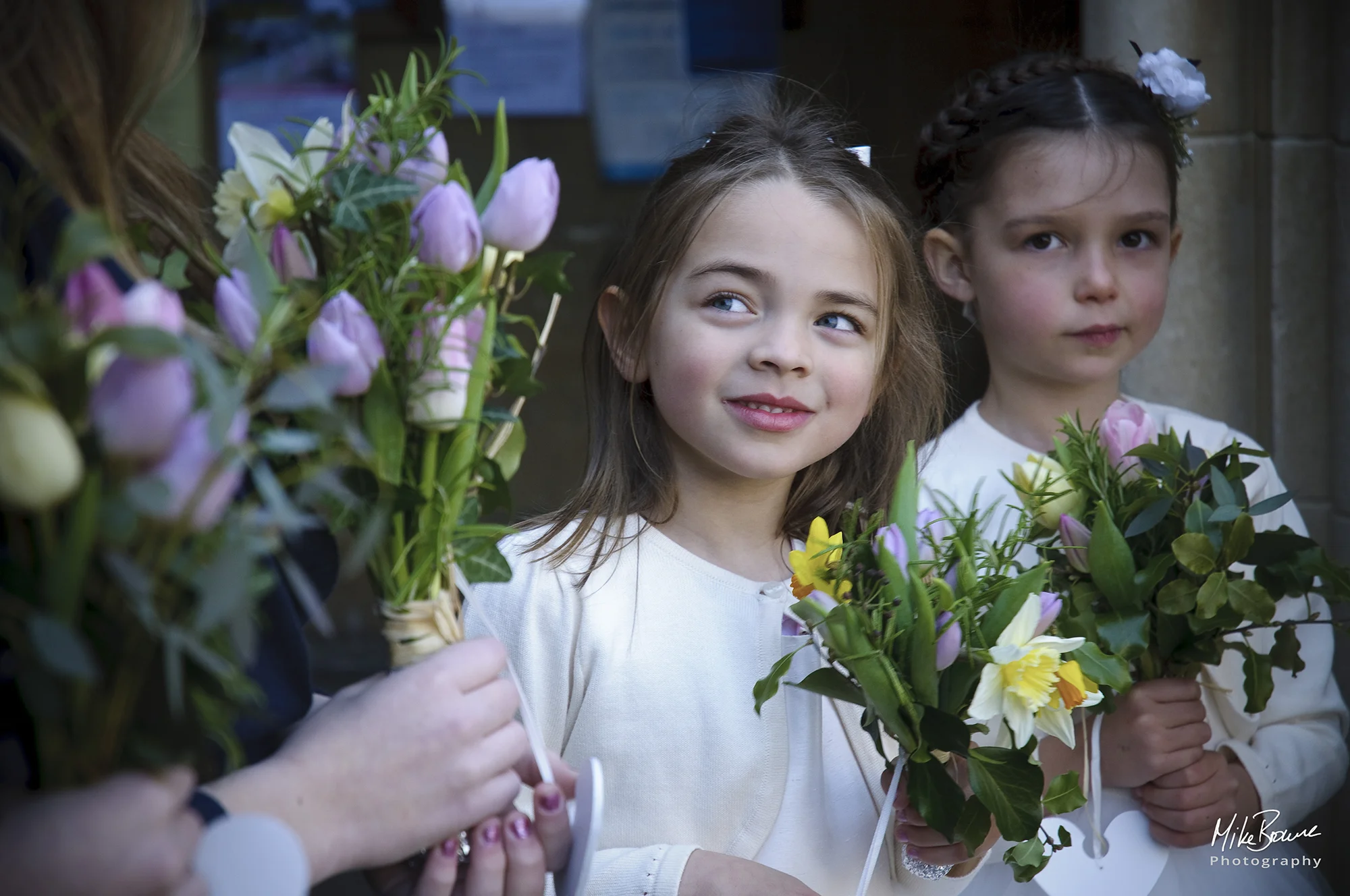 Young bridesmaids with quizzical expressions surrounded by flowers