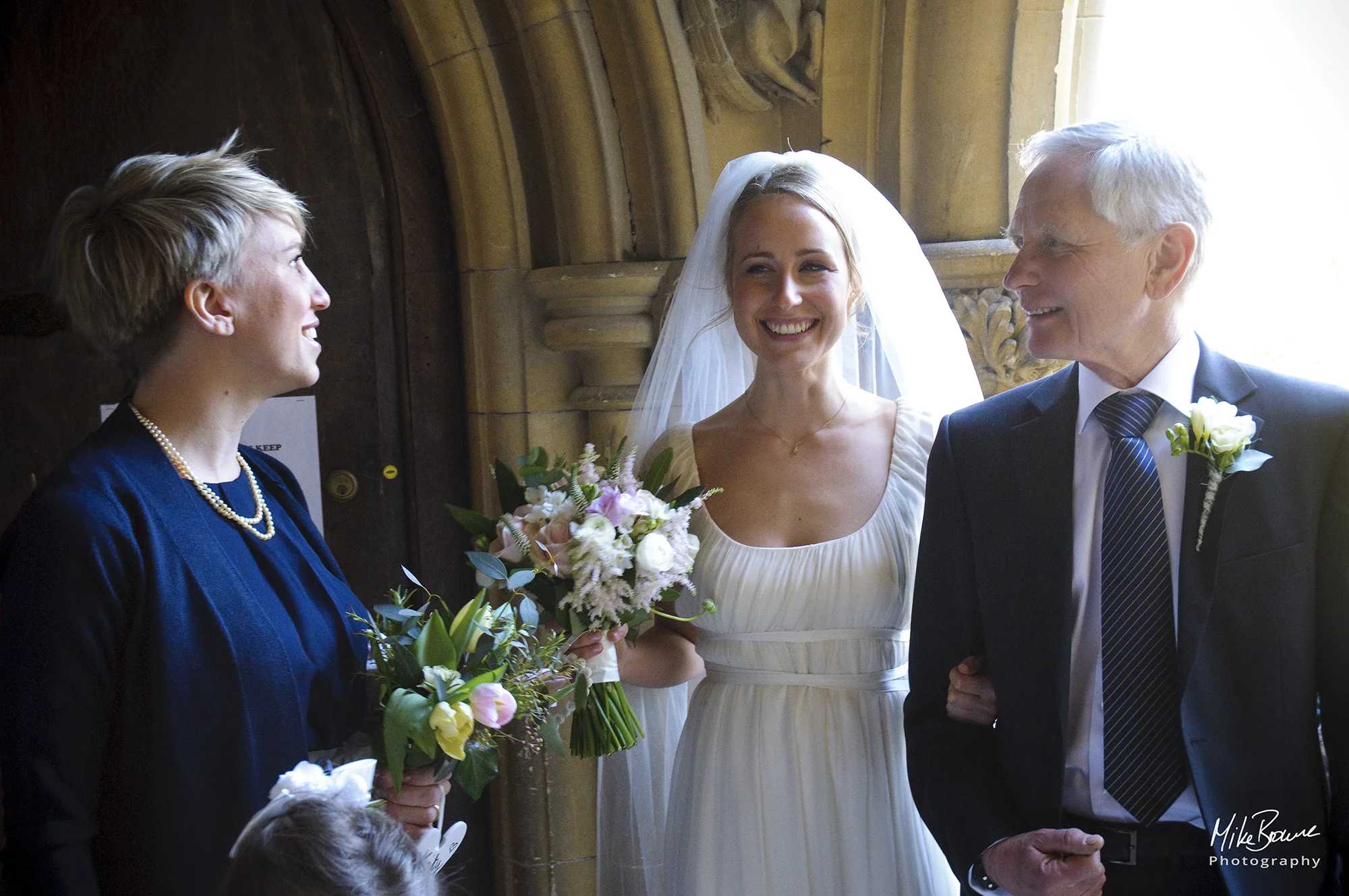 Bride and father share last minute smile with head bridesmaid