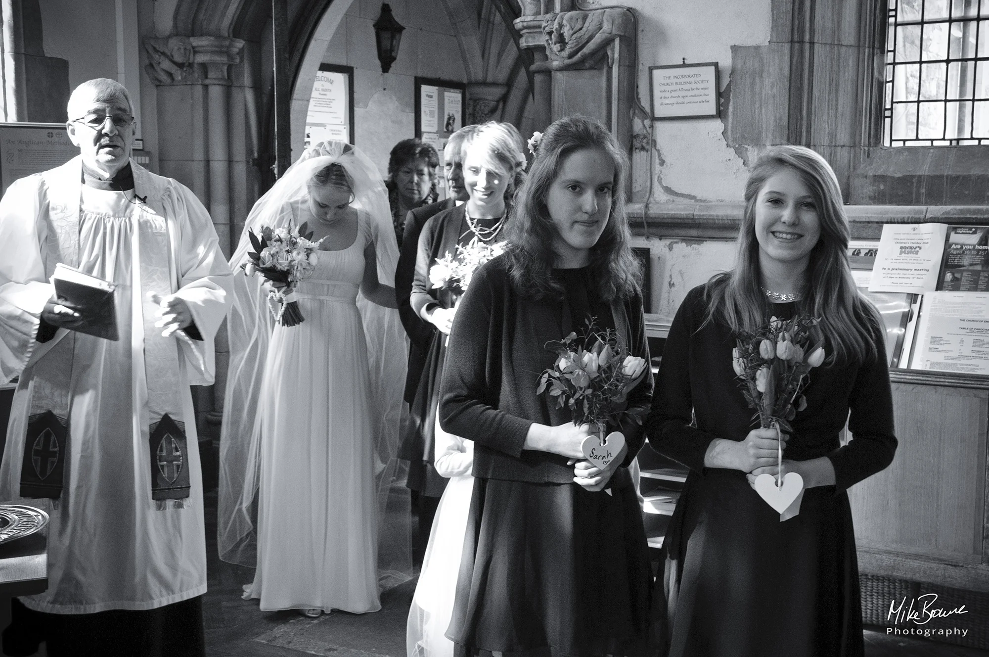 Bridal entourage and vicar entering the church