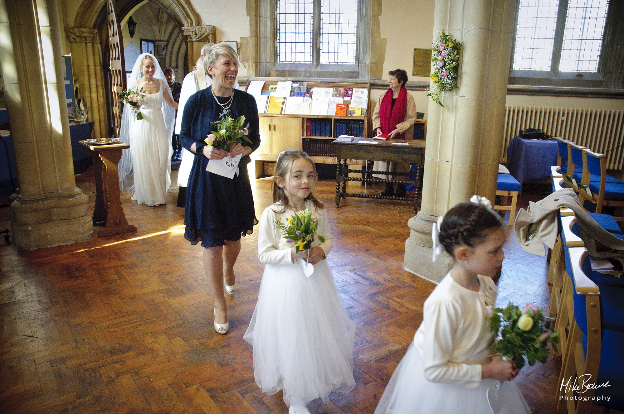 Head bridesmaid laughing as flower girl has cheeky expression