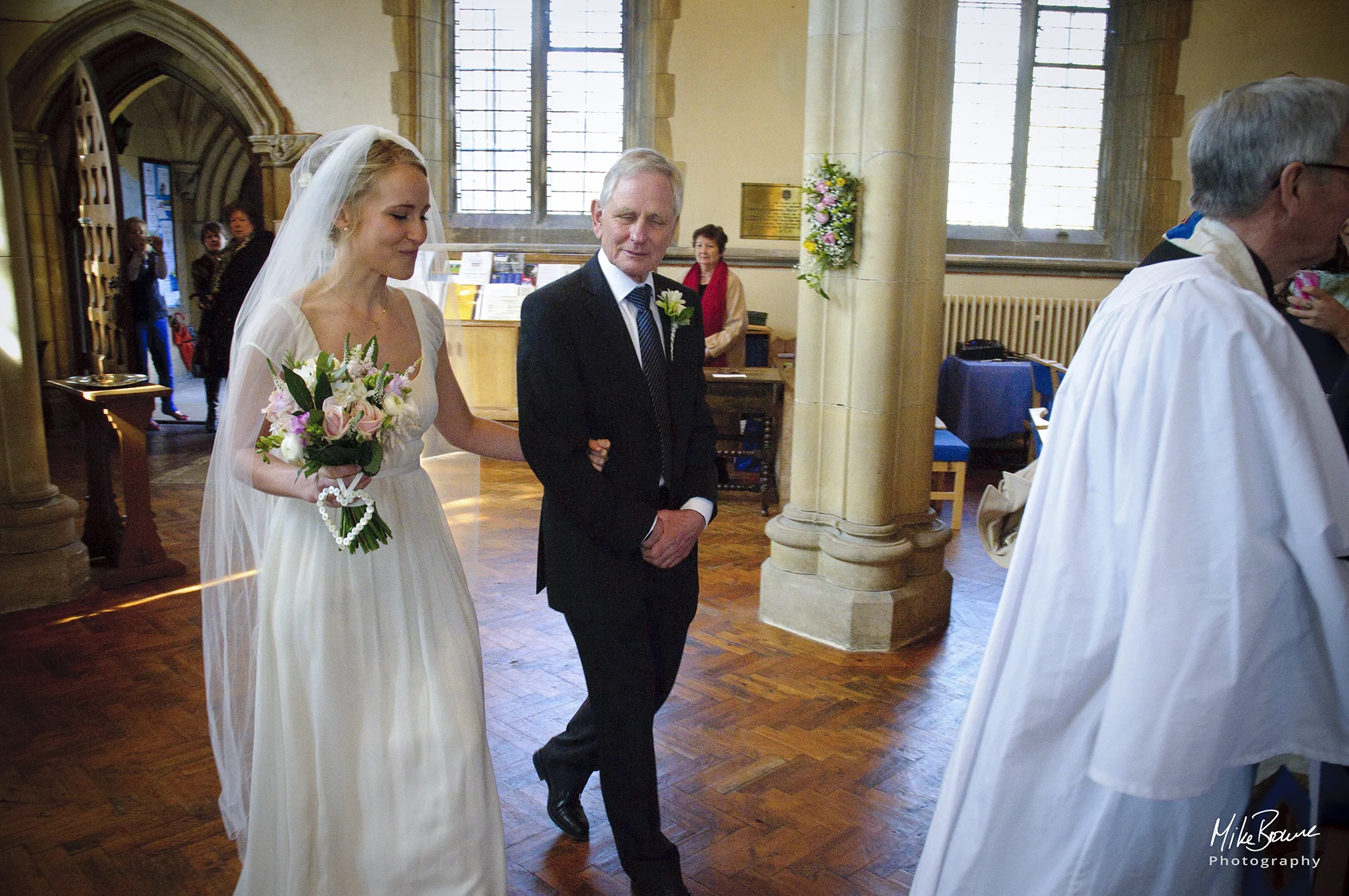 Bride and her father being led down the aisle by the vicar