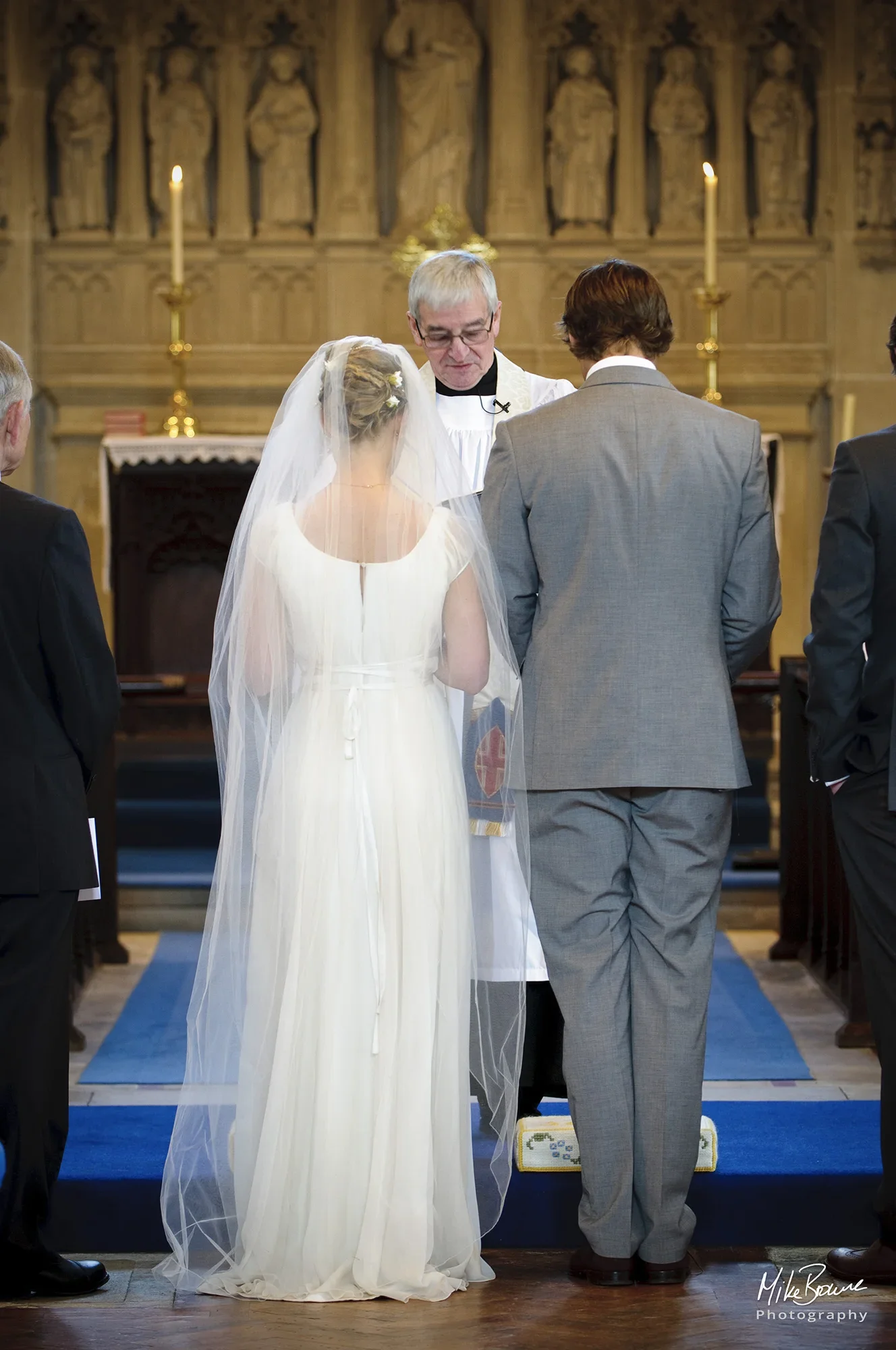 wedding couple with heads bowed before the vicar during the wedding service