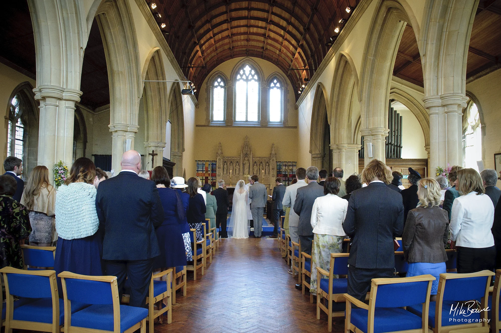 Church interior with pillars and arches as the wedding party and congregation stand