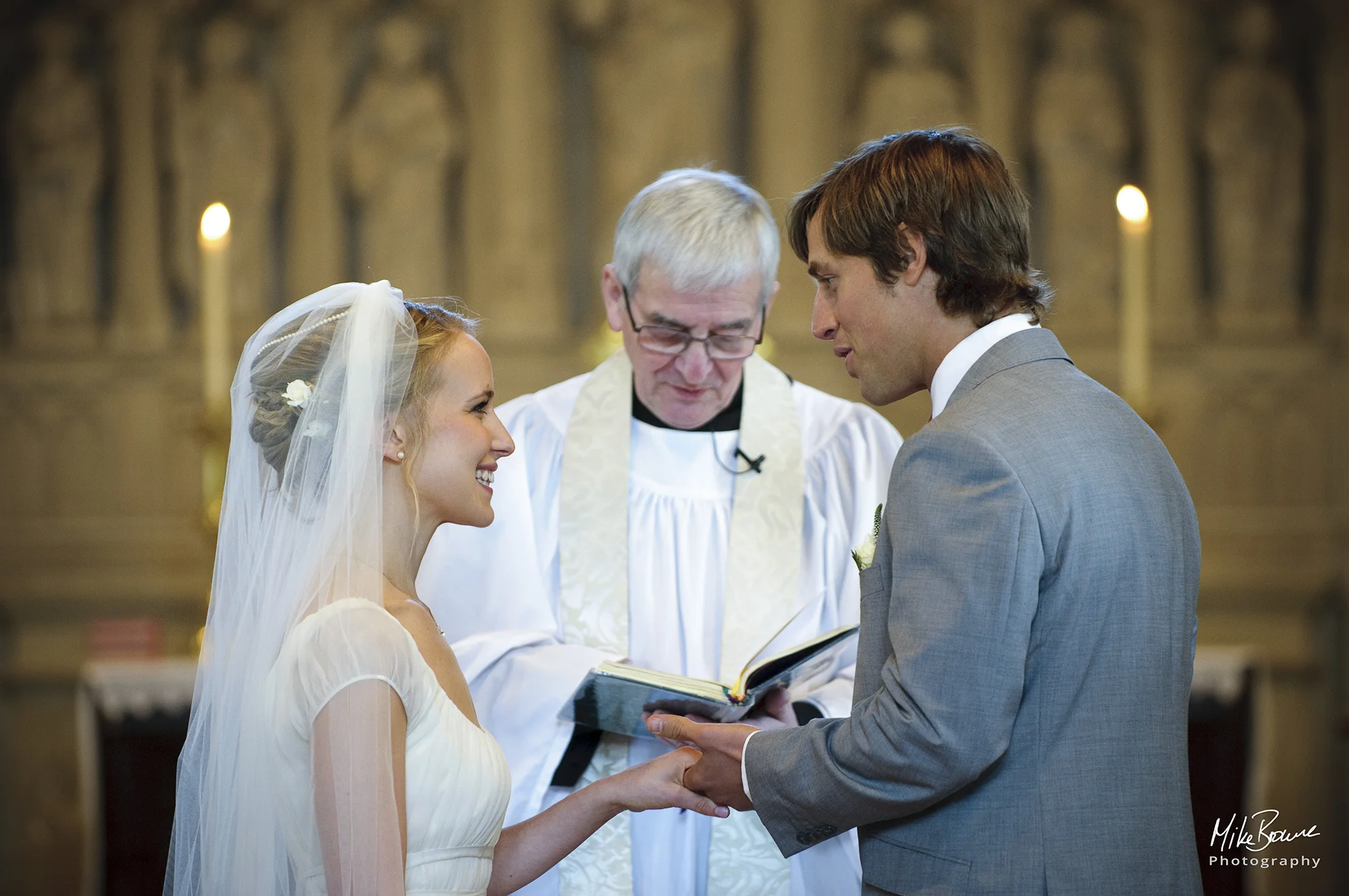 Man speaking his wedding vows to his smiling bride in church