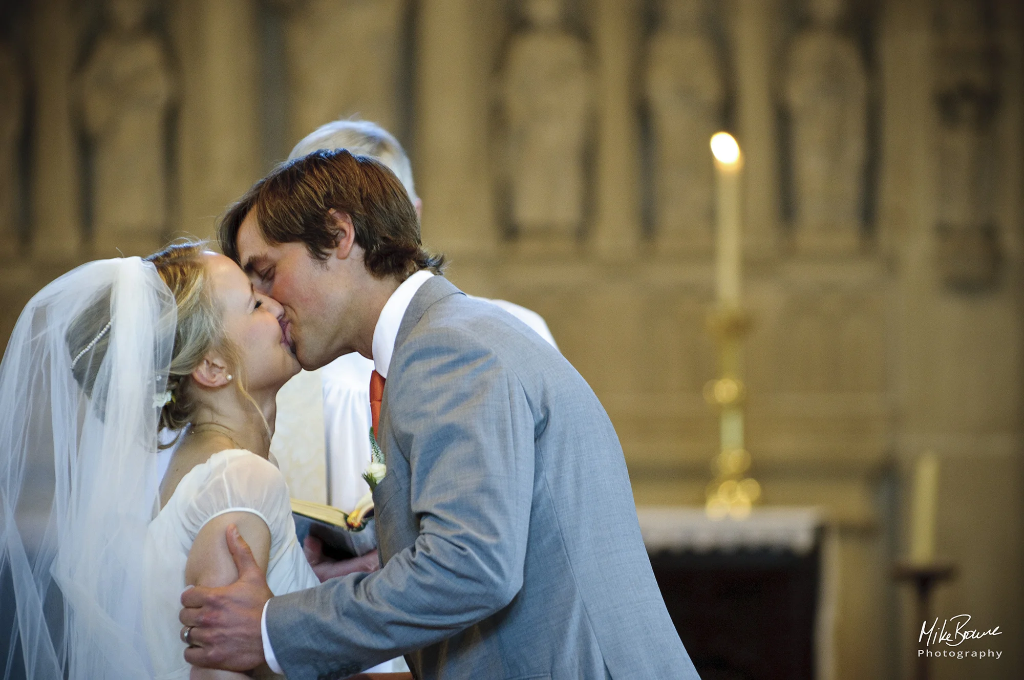 Man kisses his wife as the vicar pronounces them man and wife