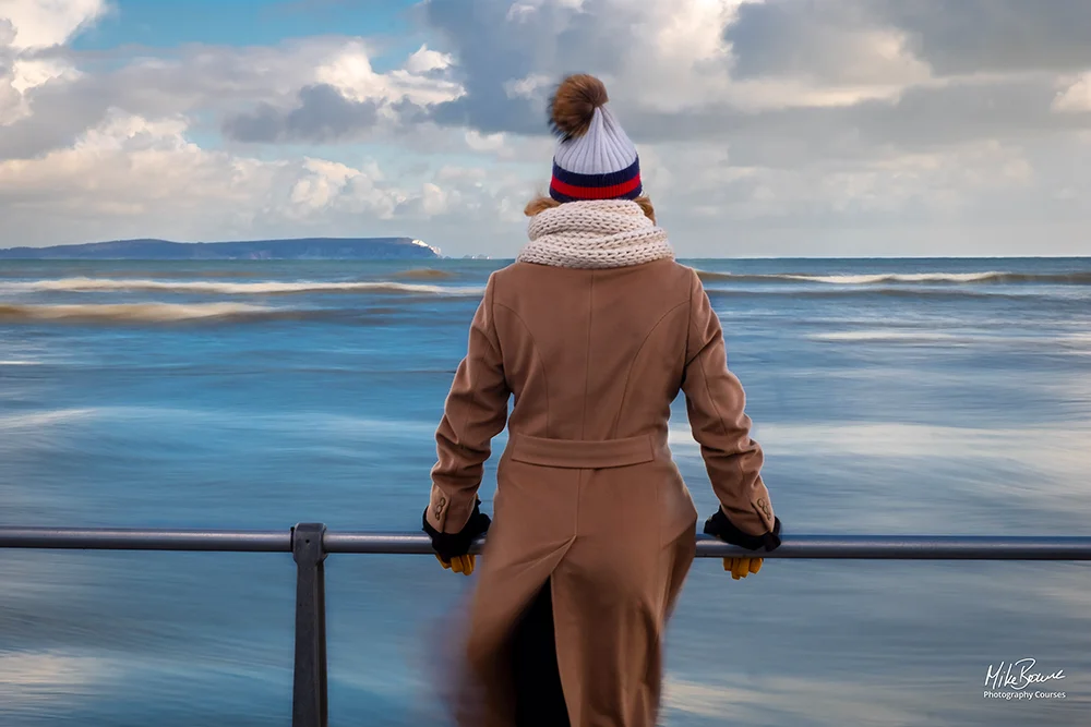woman wearing coat scarf and wolly hat staring out to sea on a windy day
